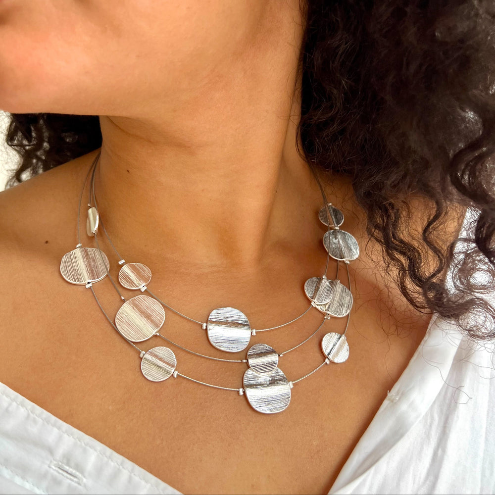 Close-up of a woman wearing an unusual, textured silver statement necklace and earrings.