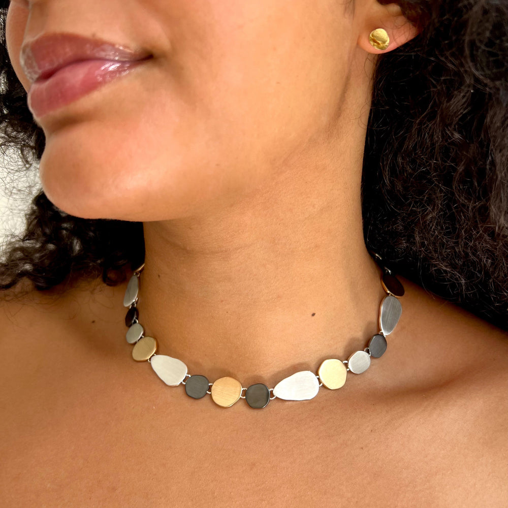 Close-up of a woman wearing a mixed metal matt finish necklace.